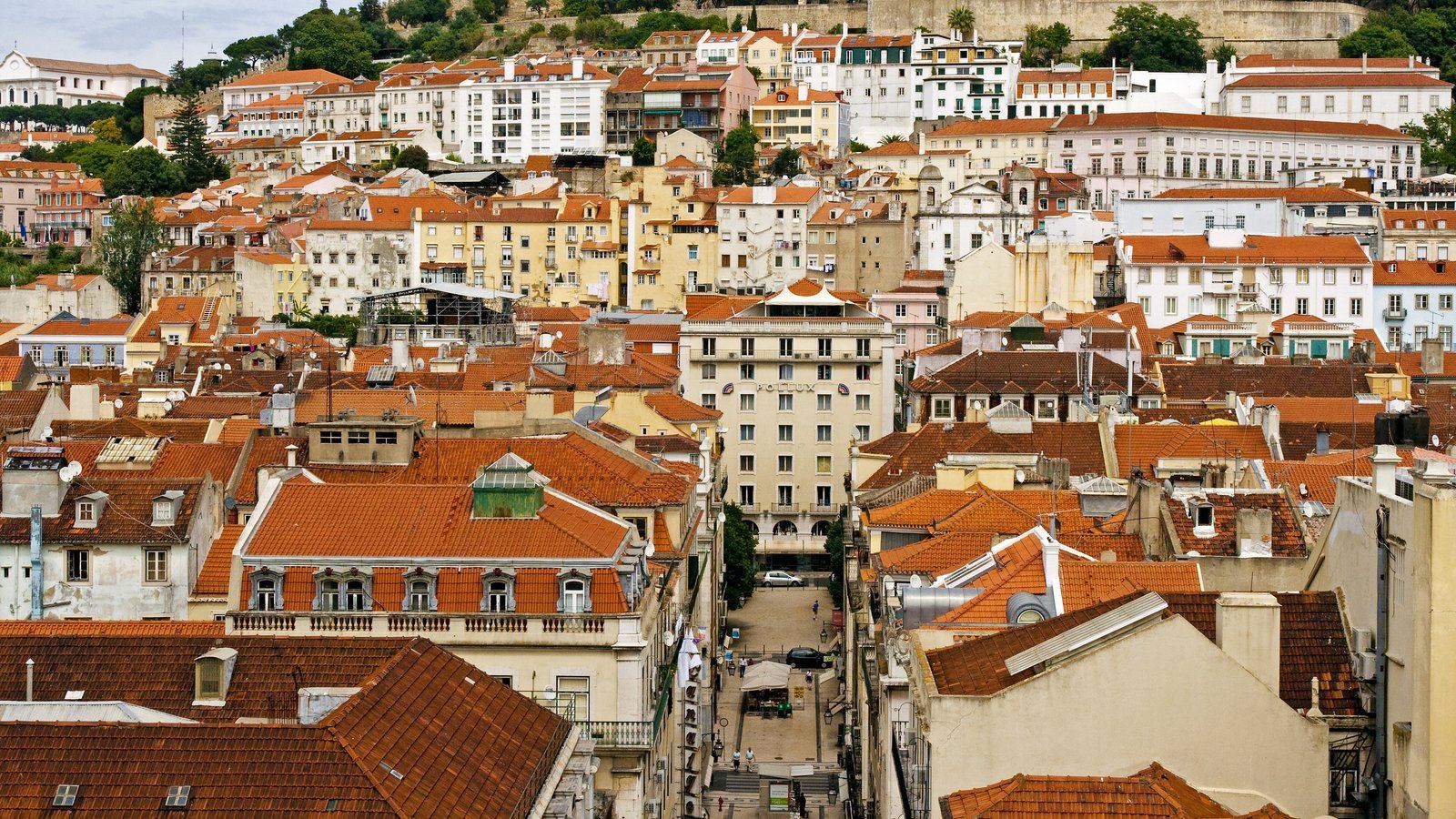 Vista sobre os telhados de Lisboa, com o casario denso a subir em direcção à colina do Castelo. Ilustrativa do tecido urbano consolidado das cidades portuguesas.